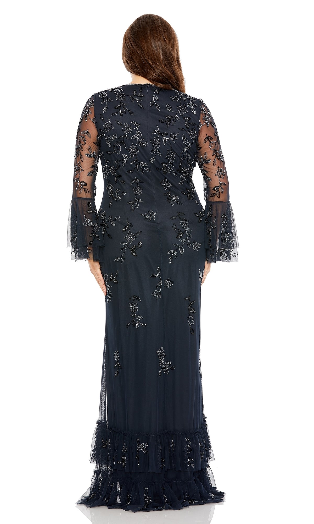 A woman stands facing away, wearing the Long Plus-Size Formal Dress 9239 by Mac Duggal in midnight blue, featuring long sleeves and delicate floral embroidery.
